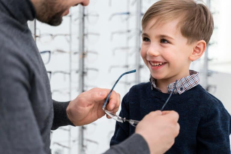 Homme aidant un enfant à essayer des lunettes dans un magasin d'optique.