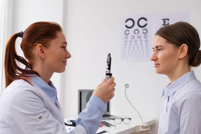 Optométriste examinant une patiente à l'aide d'un ophtalmoscope dans un cabinet médical.